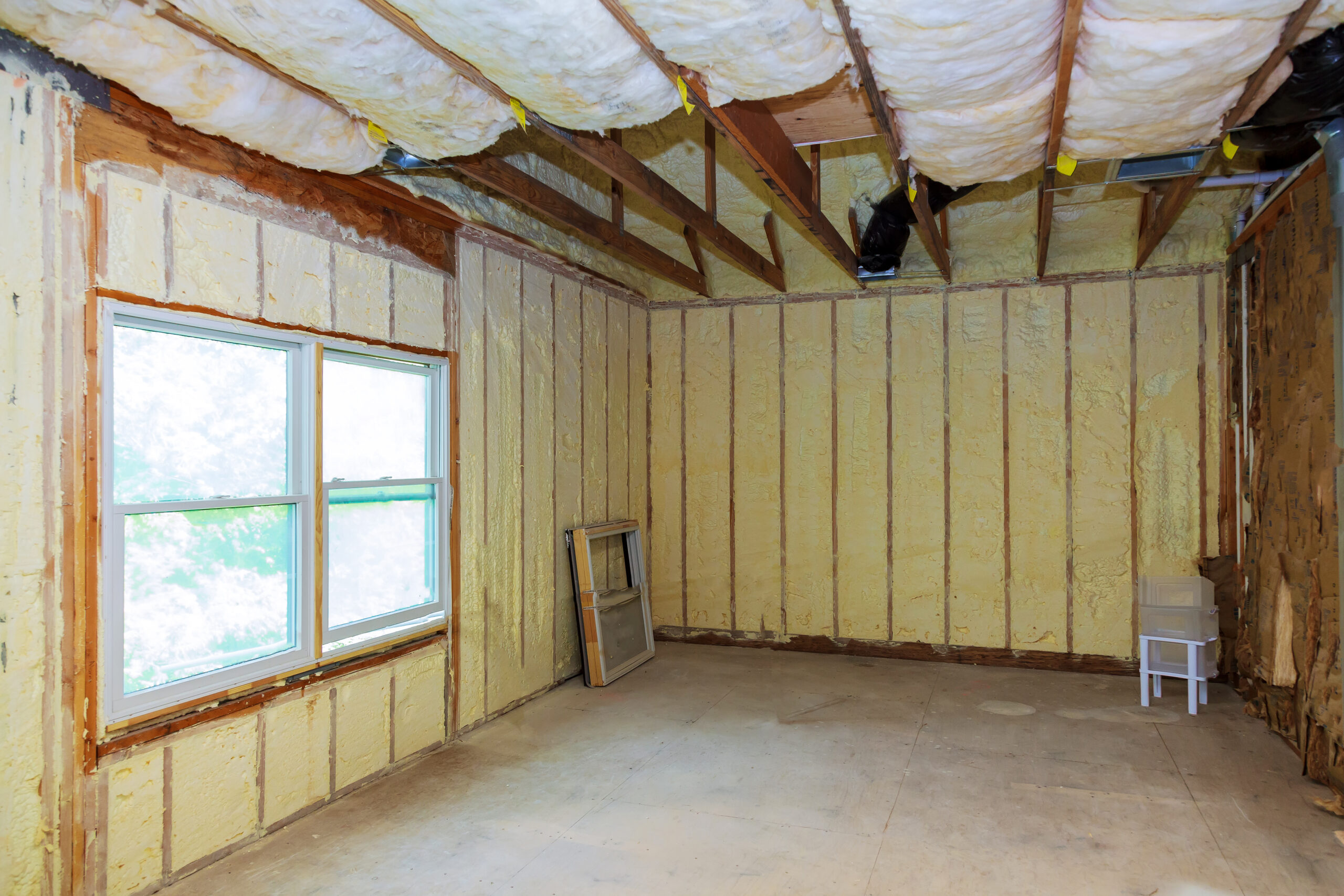 Room under construction with exposed insulation and wooden beams.